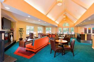 a lobby with a waiting room with tables and chairs at Residence Inn by Marriott Houston The Woodlands/Lake Front Circle in The Woodlands