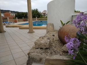 una sedia in pietra seduta accanto a una piscina con fiori viola di Casa Maria Cecília a Jávea