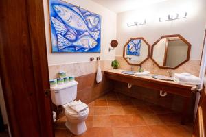 a bathroom with a toilet and a sink and mirrors at Caye Casa in San Pedro