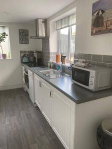 a kitchen with a sink and a microwave on a counter at Rural cosy retreat for two near Port Isaac in Delabole