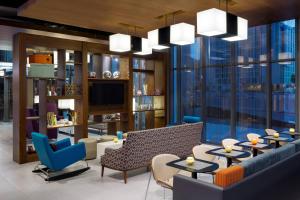 a lobby with tables and chairs and a large window at Aloft Riyadh Hotel in Riyadh