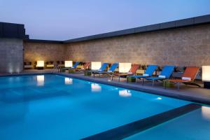 a swimming pool with lounge chairs next to a brick wall at Aloft Riyadh Hotel in Riyadh