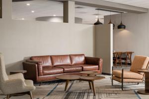 vestíbulo con sofá de cuero, mesas y sillas en Four Points by Sheraton Milwaukee North Shore, en Brown Deer