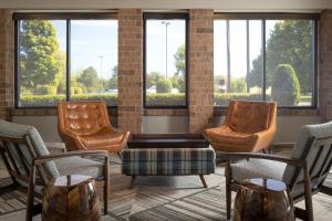 a lobby with three chairs and a table and windows at Four Points by Sheraton Milwaukee North Shore in Brown Deer