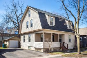 a white house with a black roof at Spacious Home with In-Unit Laundry, Parking, 1GB WiFi, & Patio Deck in Rochester