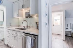 a kitchen with white cabinets and a stainless steel dishwasher at Towne Cottage Rockaway Beach - Meredith Lodging in Rockaway Beach +40 photos