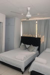 a bedroom with two beds and a large window at Apartamentos Vacacional Cartagena cerca Aeropuerto y Playa in Cartagena de Indias