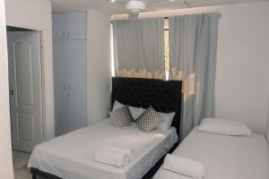 2 łóżka z białą pościelą i poduszkami w pokoju w obiekcie Apartamentos Vacacional Cartagena cerca Aeropuerto y Playa w mieście Cartagena de Indias