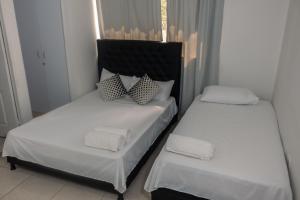 2 camas en una habitación con sábanas y almohadas blancas en Apartamentos Vacacional Cartagena cerca Aeropuerto y Playa en Cartagena de Indias