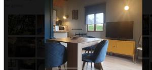 a kitchen with a table and two blue chairs at Gîte chalet bleu soleil in Saint-Benoît-dʼHérbertot
