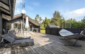 BjerregårdにあるLovely Home In Hvide Sande With Kitchenの家の上に椅子とパラソル付きのデッキ