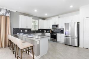 Una cocina con gabinetes blancos y un refrigerador de acero inoxidable. en Lakeview Villas in Storey Lake Resort by Diamond Vacation Homes, en Kissimmee 80 fotos más