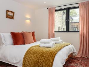 1 dormitorio con 1 cama con toallas en 1 Caddaford Barns, en Buckfastleigh