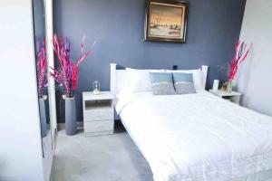 een slaapkamer met een wit bed en een blauwe muur bij Sylz Residence Studio 1- 5 Mins from Labadi & Laboma Beaches in Accra