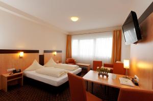 ヒュルトにあるホテル アム フレシュツのベッドとデスクが備わるホテルルームです。