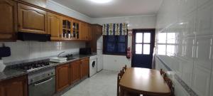 una cocina con armarios de madera, mesa y fregadero en Vista do Farol en Gafanha da Nazaré