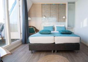 a bedroom with a large bed with blue pillows at Loods Hotel Vlieland in Oost-Vlieland
