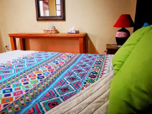 a bed with a colorful blanket on top of it at Hotel Chocolate Suites in Guanajuato