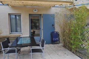 een terras met een tafel en stoelen en een blauwe deur bij Vacances en Camargue proche de la mer climatisé in Aigues-Mortes