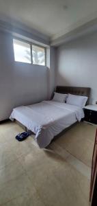 a bedroom with a large white bed with a window at Cozy 3bedrooms Apartment in Addis Ababa