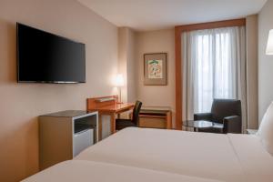 a hotel room with a bed and a flat screen tv at AC Hotel Palencia by Marriott in Palencia