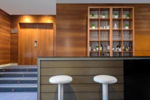 a bar with two white stools in front of it at AC Hotel Palencia by Marriott in Palencia