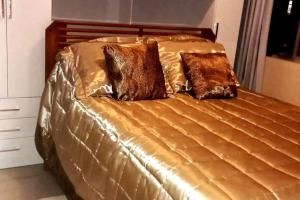 Una cama dorada con dos almohadas marrones. en Apartment in Copacabana, en Río de Janeiro