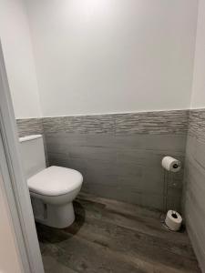 La salle de bains est pourvue de toilettes blanches et d'un rouleau de papier toilette. dans l'établissement Jardin privé 1, à La Ravoire