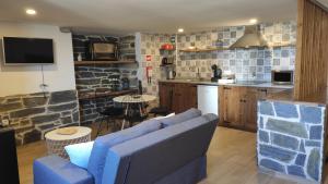 ein Wohnzimmer mit einem blauen Sofa und einer Küche in der Unterkunft Recanto da Encosta T0 in Bragança