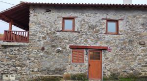 ein Steinhaus mit einer Holztür und Fenstern in der Unterkunft Recanto da Encosta T0 in Bragança