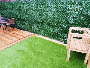 een patio met een tafel en stoelen en een groene muur bij Rosa House in Darlington