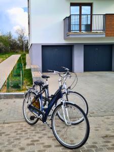two bikes parked in front of a building at Przystań Natura Apartamenty nad rzeką, cisza i rowery in Iława