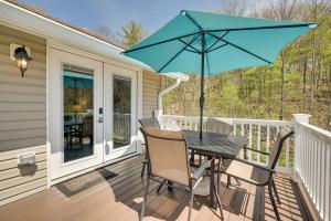 a table and chairs on a porch with a blue umbrella at Woodsy Family Retreat 11 Mi to Raystown Lake! 