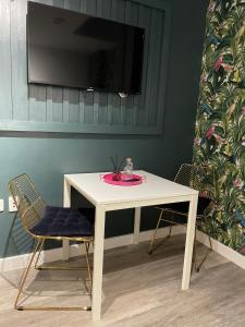 ein weißer Tisch mit zwei Stühlen und einem Fernseher an der Wand in der Unterkunft The Phoenix Collection in Liverpool