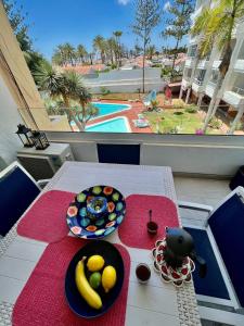 einen Tisch mit Obstteller und Poolblick in der Unterkunft Mama Yumbo in Playa del Ingles