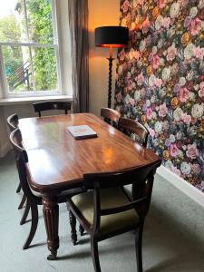 a wooden table and chairs in a room with a floral wall at Powis House Mid Cottage in Stirling
