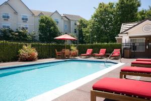 uma piscina com cadeiras e um guarda-sol em TownePlace Suites Milpitas Silicon Valley em Milpitas