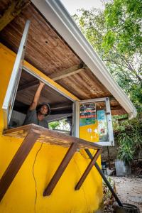 un hombre asomando la cabeza por una ventana de un autobús amarillo en Pura Vida Mini Hostel Santa Teresa, en Santa Teresa Beach