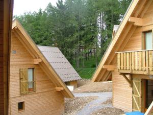 a view of two wooden houses with trees in the background at Flocons du Soleil by Actisource in La Joue du Loup