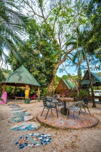 einen Picknickbereich mit einem Tisch, Stühlen und Bäumen in der Unterkunft Pura Vida Mini Hostel Santa Teresa in Playa Santa Teresa