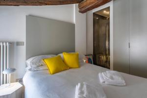 - une chambre avec un lit blanc et des oreillers jaunes dans l'établissement San Pietro, à Bologne
