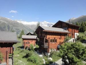 a large wooden house with mountains in the background at Chalet Stefanino, 3 12 Zimmer in Bellwald
