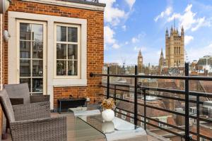 Westminster Big Ben Apartment في لندن: بلكونه مع طاوله زجاجيه واطلاله على مدينه
