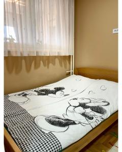 a bed with a black and white blanket on it at Apartman Jelena in Sremska Mitrovica