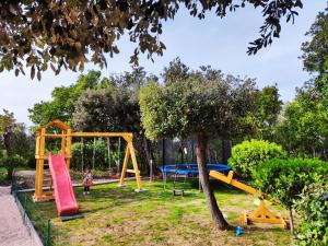 a child standing in a park with a playground at Apartmani "Sandro" Gonar in Rab