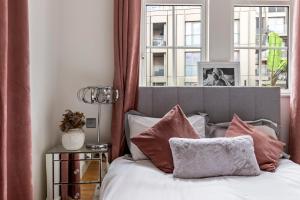 una camera da letto con letto, cuscini e finestra di Westminster Big Ben Apartment a Londra