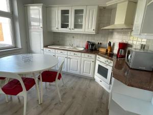a kitchen with white cabinets and a table with chairs at Agréable duplex proche de toutes commodités in Ans