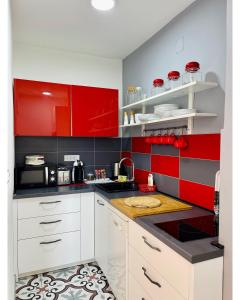 a kitchen with red and black walls and white cabinets at Apartman Jelena in Sremska Mitrovica