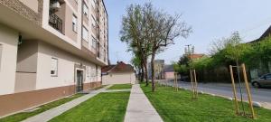 a sidewalk next to a building with a grass yard at Apartman Visnja in Subotica