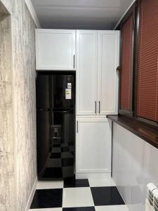 uma cozinha com um frigorífico preto e um piso em xadrez em Miracle Apartment em Samarkand